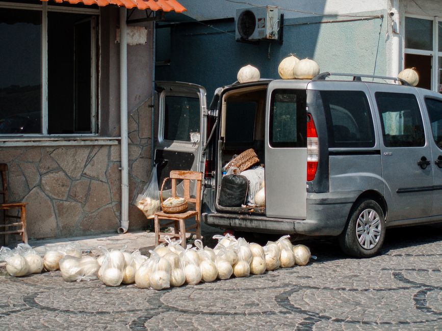 A van unloading pumpkins on a cobblestone street beside a building with open doors.